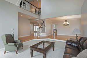 Carpeted living room with a high ceiling, crown molding, and a notable chandelier