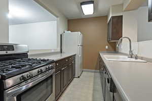 Kitchen with dark brown cabinetry, stainless steel appliances, and sink