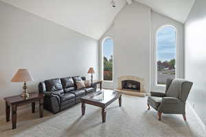 Carpeted living room featuring high vaulted ceiling, plenty of natural light, and beam ceiling