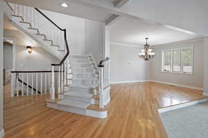 Entrance foyer featuring light wood-type flooring, crown molding, and an inviting chandelier