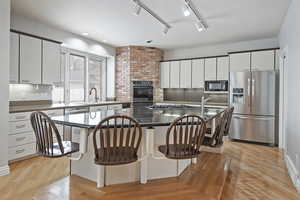 Kitchen featuring a center island, a kitchen breakfast bar, white cabinetry, and black appliances