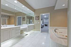 Bathroom with tile patterned floors, vanity, and a relaxing tiled tub