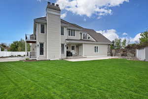 Rear view of property with a patio area, a lawn, and a balcony