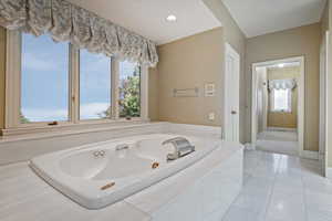 Bathroom with tiled bath and tile patterned flooring