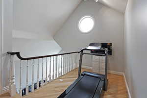 Exercise room featuring vaulted ceiling and hardwood / wood-style floors