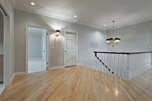 Interior space featuring a notable chandelier, ornamental molding, and light hardwood / wood-style floors