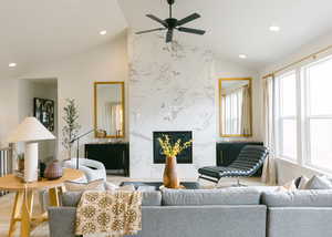 Living room with a premium fireplace, vaulted ceiling, a healthy amount of sunlight, and ceiling fan