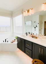 Bathroom featuring tile patterned flooring, vanity, and a tub to relax in
