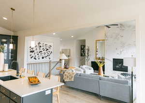 Living room with vaulted ceiling, sink, a fireplace, and light hardwood / wood-style floors