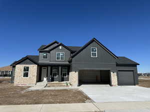 Craftsman house featuring concrete driveway, board and batten siding, a porch, stone siding, and a garage