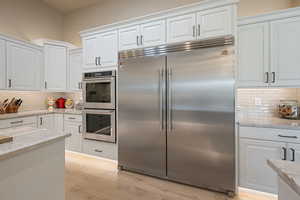 Kitchen with white cabinetry, appliances with stainless steel finishes, and light stone countertops