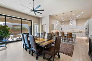 Dining area featuring a towering ceiling, ceiling fan, and light hardwood / wood-style flooring