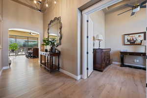 Corridor with a towering ceiling, a chandelier, and light hardwood / wood-style floors