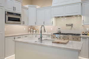 Kitchen with white cabinetry and light stone countertops