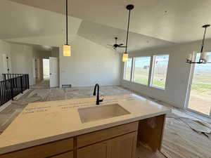 Kitchen with open floor plan, a textured ceiling, a sink, and light stone counters