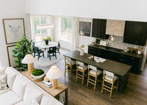 Kitchen with a kitchen island with sink, decorative backsplash, sink, black stovetop, and dark hardwood / wood-style floors