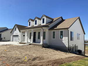 View of front of home featuring covered porch, central air condition unit, and a garage