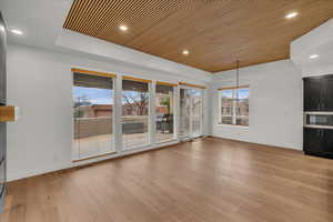 Unfurnished living room featuring a tray ceiling, light hardwood / wood-style flooring, and wood ceiling