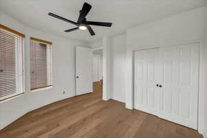 Unfurnished bedroom featuring light wood-type flooring, a closet, and ceiling fan