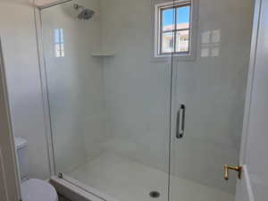 Full bathroom featuring a stall shower and toilet