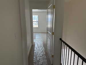 Hall with baseboards, carpet flooring, and an upstairs landing