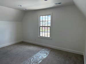 Bonus room with vaulted ceiling, a textured ceiling, carpet, baseboards, and visible vents