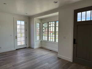 Entryway featuring wood finished floors, visible vents, baseboards, and ornamental molding