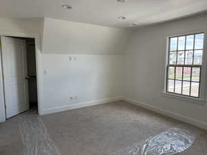 Additional living space featuring plenty of natural light, vaulted ceiling, carpet flooring, and baseboards