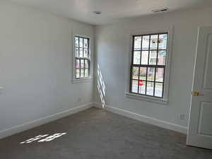 Empty room with baseboards, visible vents, and carpet floors