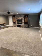 Unfurnished living room with a fireplace, ornamental molding, carpet flooring, and a textured ceiling