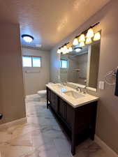 Bathroom with a textured ceiling, vanity, toilet, and walk in shower