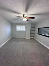 Unfurnished bedroom with dark carpet, ceiling fan, and a textured ceiling