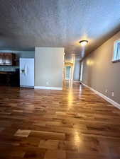 Unfurnished living room with hardwood / wood-style floors and a textured ceiling