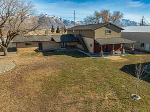 Back of house with a mountain view, a lawn, and a patio area