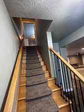 Staircase with hardwood / wood-style flooring and a textured ceiling