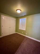 Unfurnished bedroom featuring carpet, a closet, and a textured ceiling