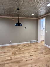 Empty room featuring ornamental molding and light hardwood / wood-style flooring