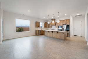 Kitchen featuring appliances with stainless steel finishes, a center island, pendant lighting, a kitchen breakfast bar, and tasteful backsplash