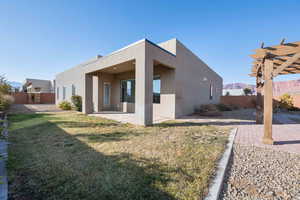 Rear view of house featuring a mountain view, a patio, a pergola, and a lawn