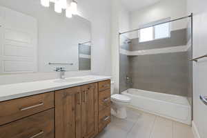 Full bathroom with tile patterned floors, toilet, vanity, and tiled shower / bath