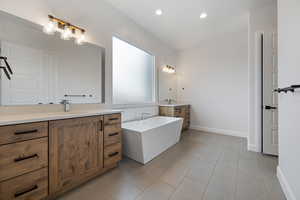 Bathroom with tile patterned floors, a bathing tub, and vanity