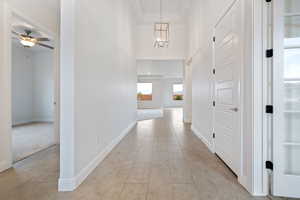 Hall featuring a high ceiling, light tile patterned flooring, and a notable chandelier