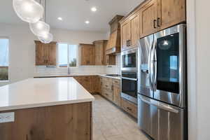 Kitchen featuring custom exhaust hood, hanging light fixtures, a center island, tasteful backsplash, and appliances with stainless steel finishes