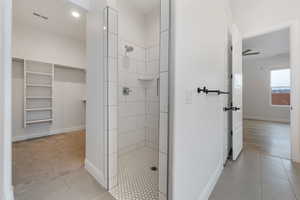 Bathroom with tile patterned flooring and a tile shower