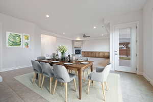 Dining area featuring a fireplace, ceiling fan, and light tile patterned floors