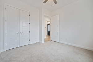 Unfurnished bedroom featuring a closet, light colored carpet, and ceiling fan