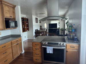 Kitchen with stainless steel electric range, island exhaust hood, dark countertops, and black microwave