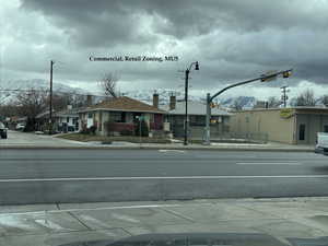 View of street featuring traffic lights, sidewalks, a mountain view, curbs, and a residential view