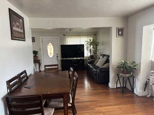 Dining area with a textured ceiling, wood finished floors, and baseboards