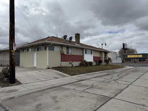 View of front of property featuring fence, brick siding, and a chimney